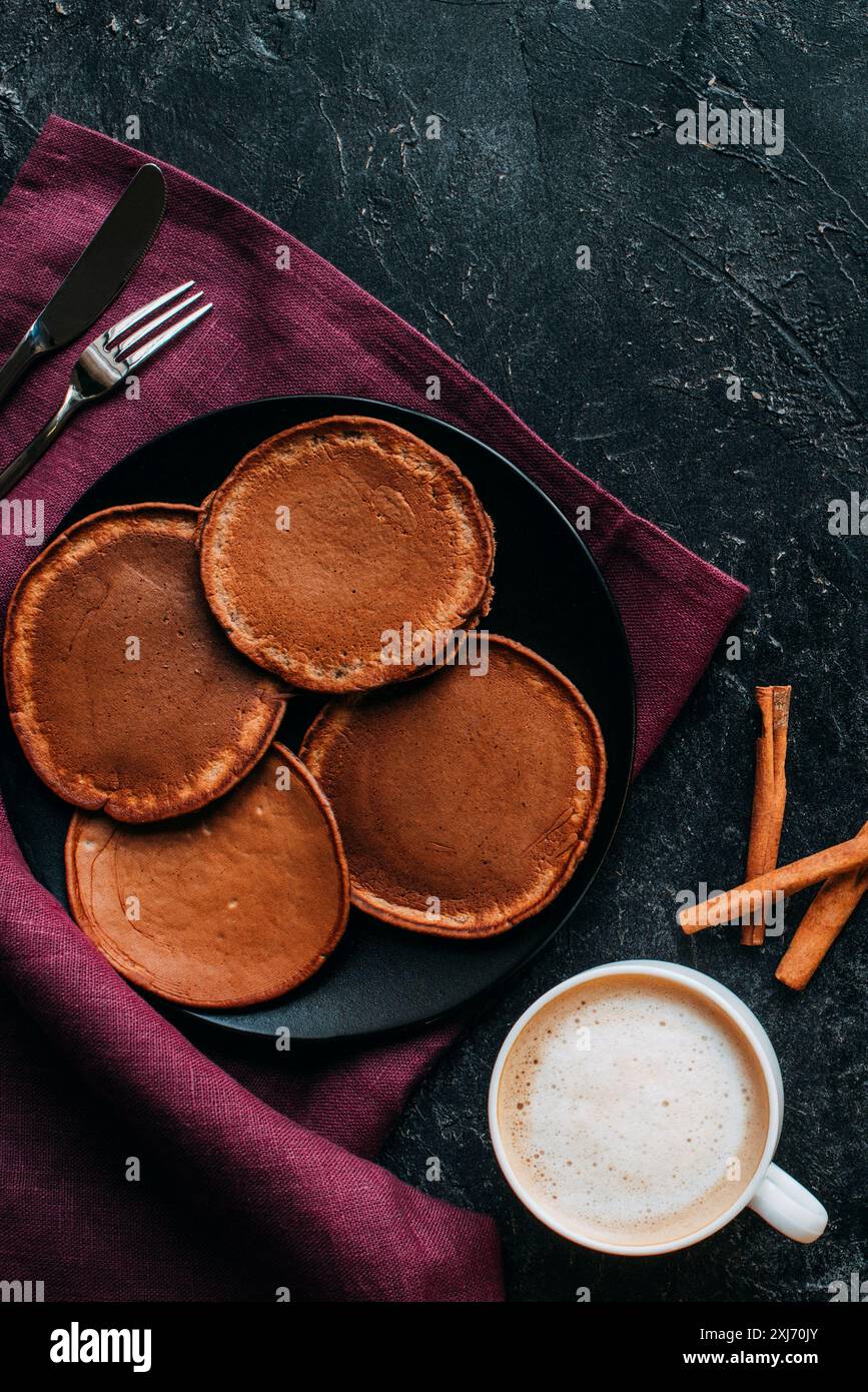 Blick von oben auf die Schokolade Pfannkuchen und Tasse Kaffee auf schwarze Oberfläche Stockfoto