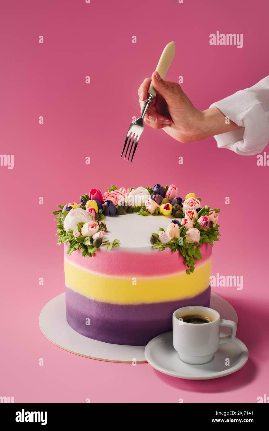 7/8 Schoß der Frau mit Gabel, Tasse Kaffee und Kuchen eingerichtet, mit cremefarbenen Blüten isoliert auf Rosa Stockfoto