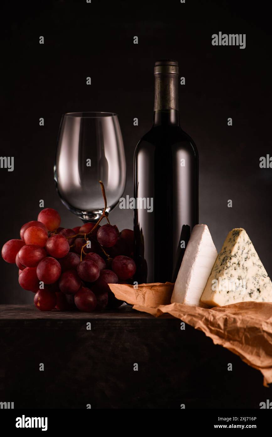 Lecker Rotwein mit Trauben und Käse auf Schwarz Stockfoto