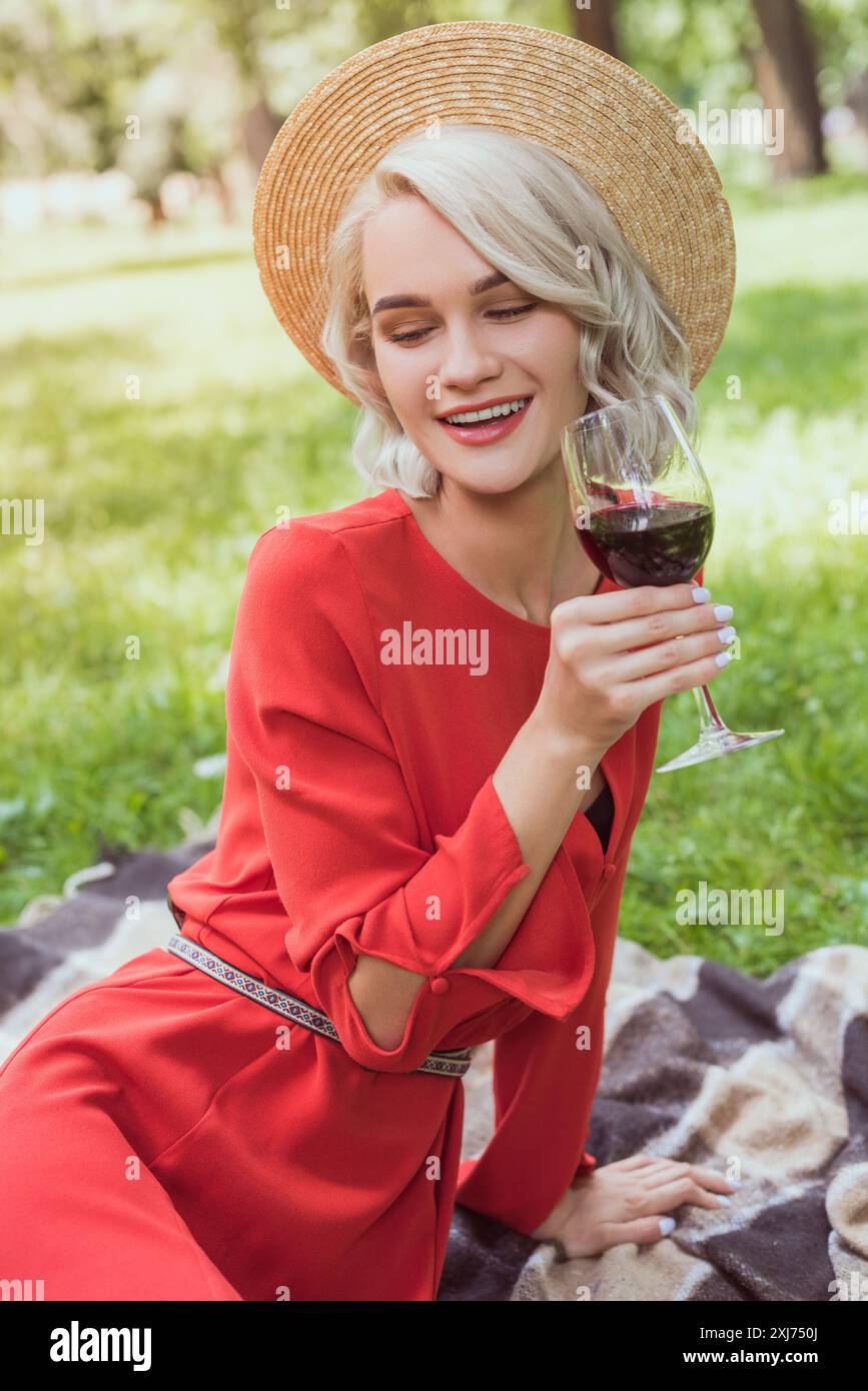 Attraktives Mädchen im roten Kleid holding Glas Rotwein in Park Stockfoto