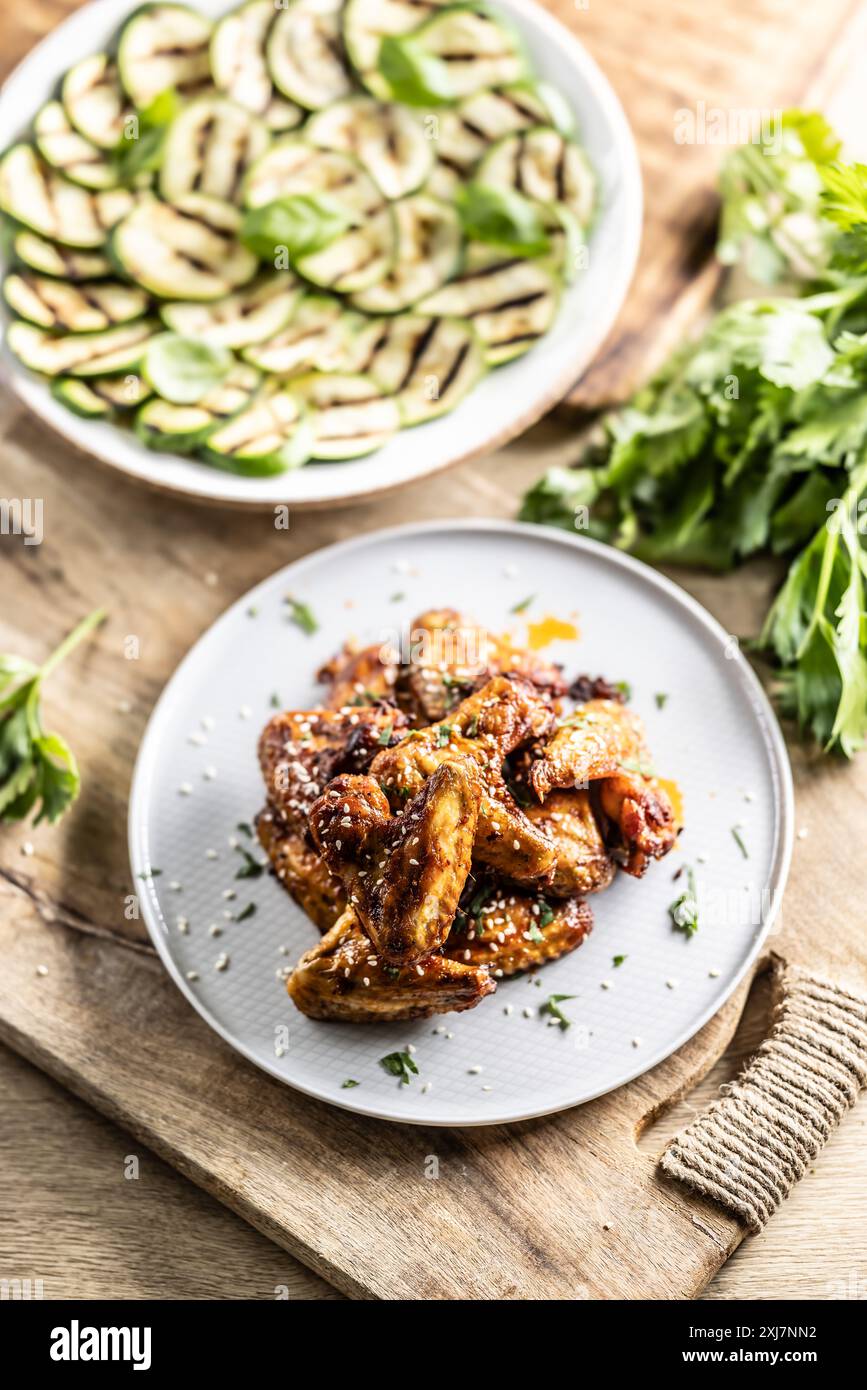 Gegrillte Hähnchenflügel auf einem Teller und gegrillte Zucchini als Beilage. Stockfoto