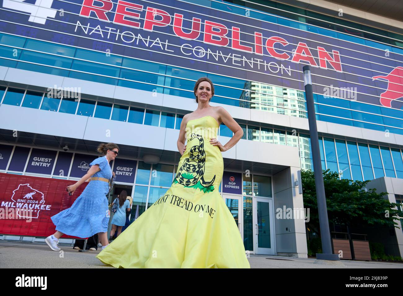 16. Juli 2024, Milwaukee, Wisconsin, USA: Eine Frau in einem gelben Kleid mit Gadsden-Flagge beim Eintritt zum zweiten Tag der GOP Republican National Convention 2024. Die Gadsden-Flagge ist eine historische amerikanische Flagge mit einem gelben Feld, das eine hölzerne Klapperschlange darstellt, die zum Zuschlagen bereit ist. Unter der Klapperschlange stehen die Worte "DON T TREAD ON ME". Die Flagge ist nach C. Gadsden benannt, einem südkarolinischen Delegierten des Kontinentalkongresses und Brigadegeneral der Kontinentalarmee, der die Flagge 1775 während der Amerikanischen Revolution entwarf. Die Klapperschlange war ein Symbol für die Einheit der Dreißigjährigen Stockfoto