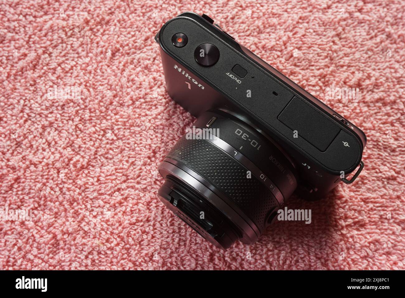 Terengganu, Malaysia - 2. August 2024 : Nahaufnahme der spiegellosen nikon 1 j1 Kamera auf rotem Hintergrund. 1 Zoll Kompaktkamera. Austauschbares Kameraobjektiv. Stockfoto