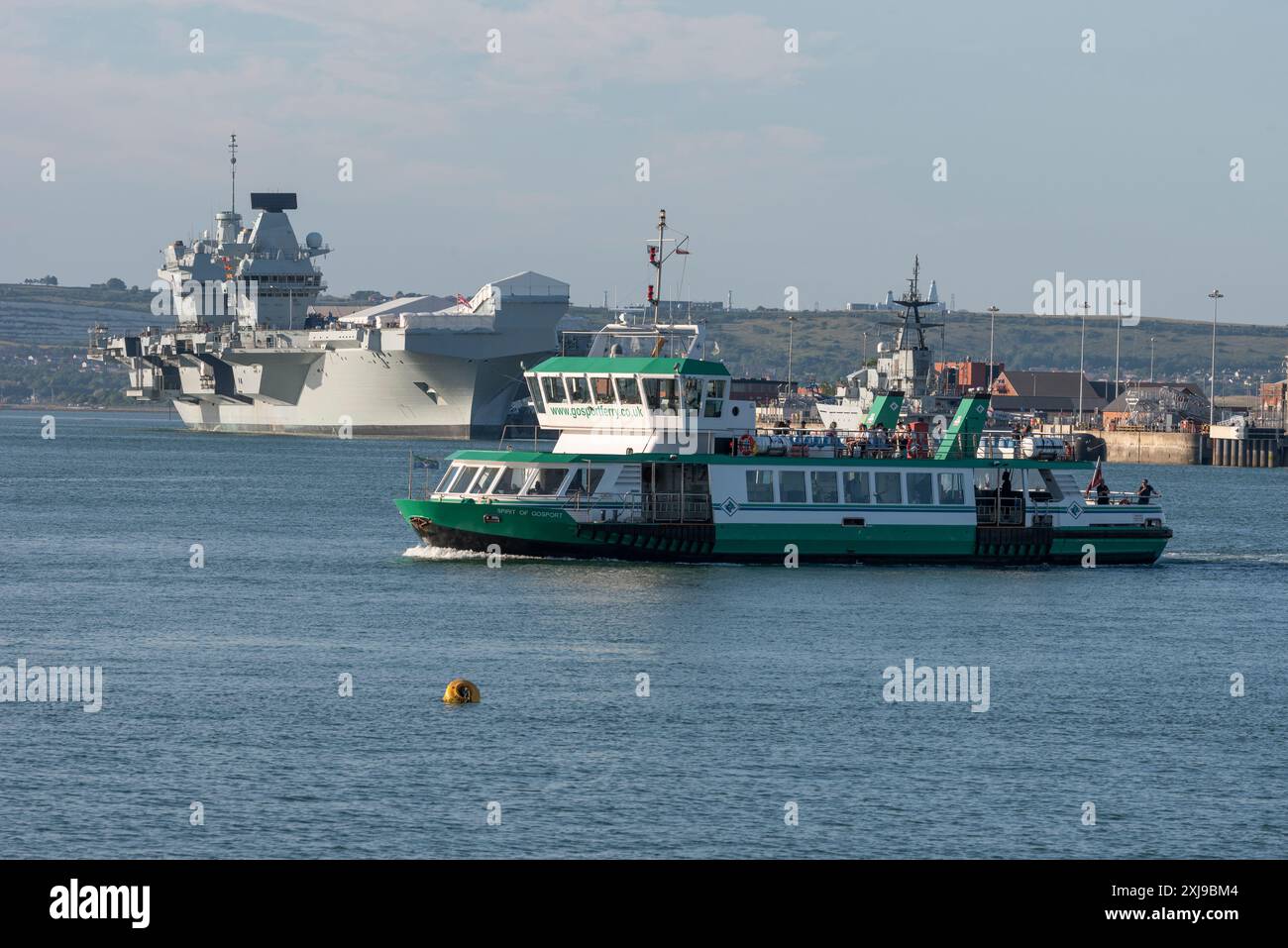Portsmouth Harbour England Großbritannien. 20.06.2024. Gosport-Passagierfähre überquert den Hafen von Portsmouth im Hintergrund HMS Prince of Wales Flugzeugträger. Stockfoto