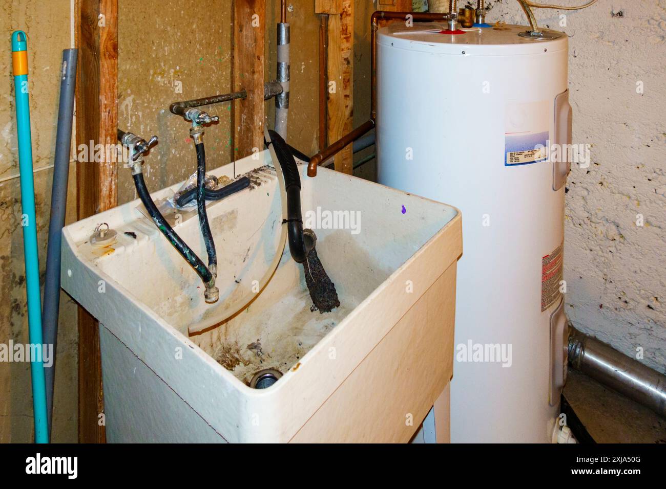 Kellerecke mit Warmwasserbereiter und schlammigem Waschbecken. Stockfoto