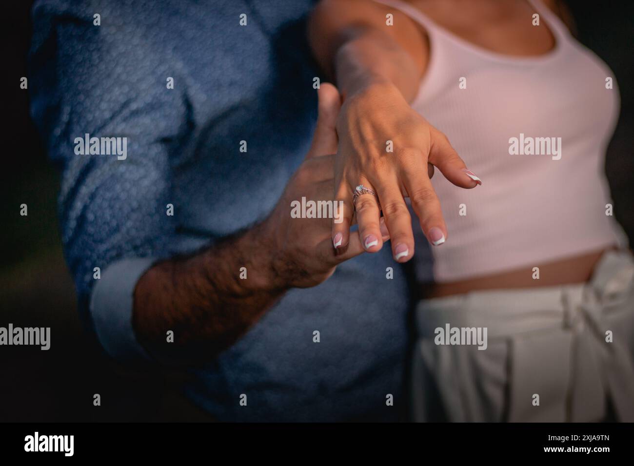 Eine Frau zeigt ihren Verlobungsring, während sie von einem Mann vorgeschlagen wird. Stockfoto