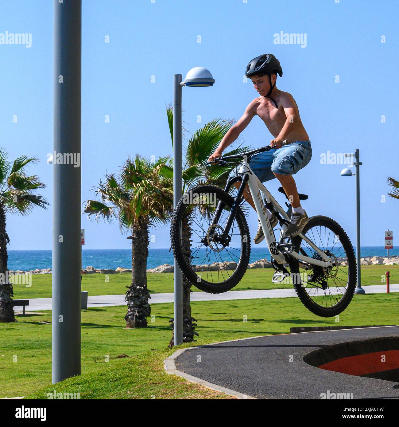 Ein Junge, der einen Stunt mit einem Fahrrad in einem Skatepark in Tel Aviv, Israel, aufführt Stockfoto