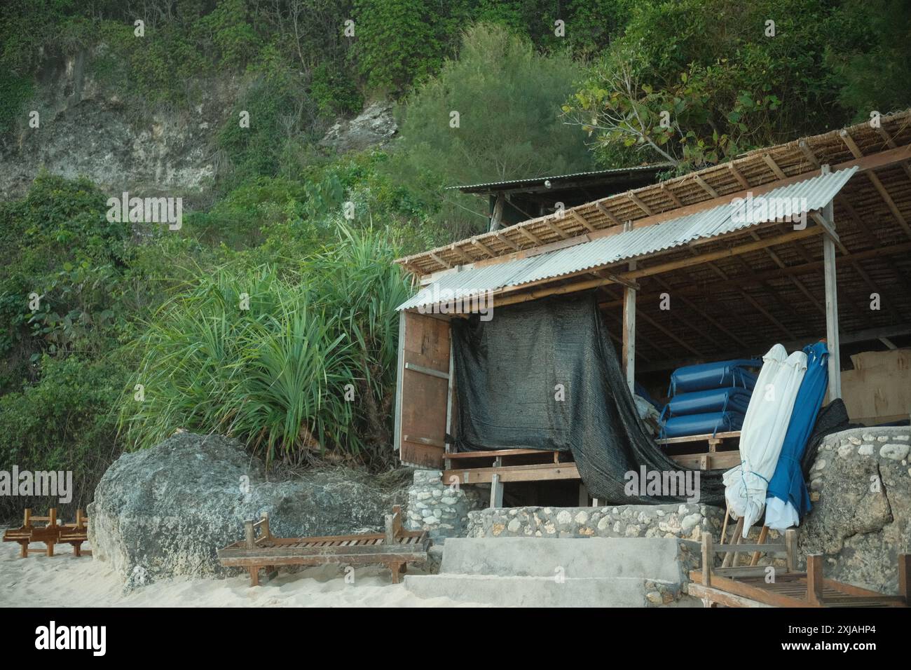 Pecatu, Bali, Indonesien - 15. Juli 2024: Ein kleines, einfaches Lagerhaus unter einer Klippe am Rande eines tropischen Inselstrandes Stockfoto