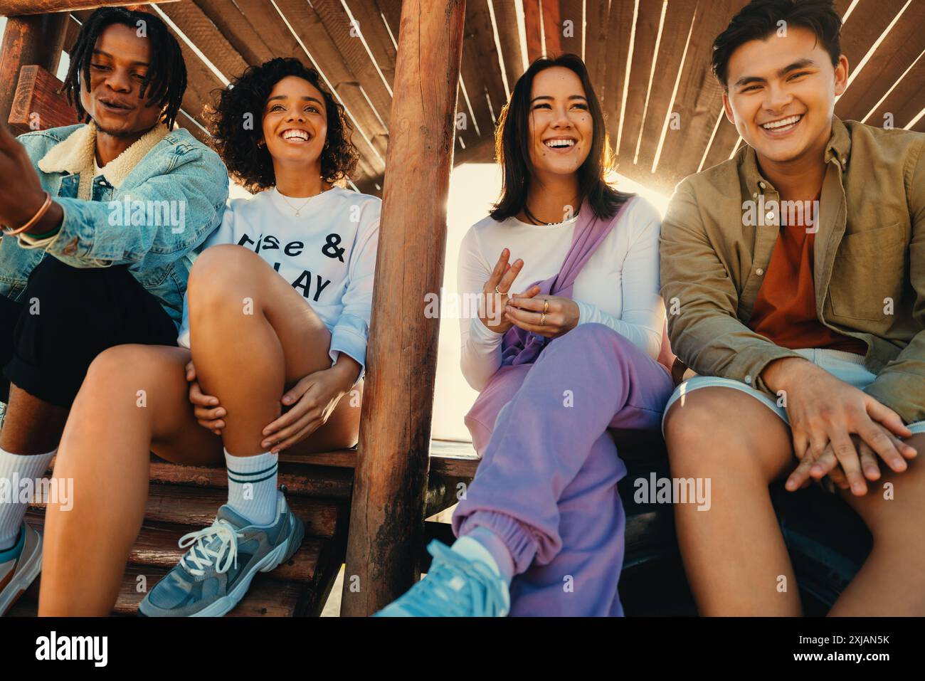 Eine Gruppe von Freunden lacht und genießt ihre gemeinsame Zeit im Freien unter einem hölzernen Baldachin und zeigt Freundschaft und Glück. Stockfoto