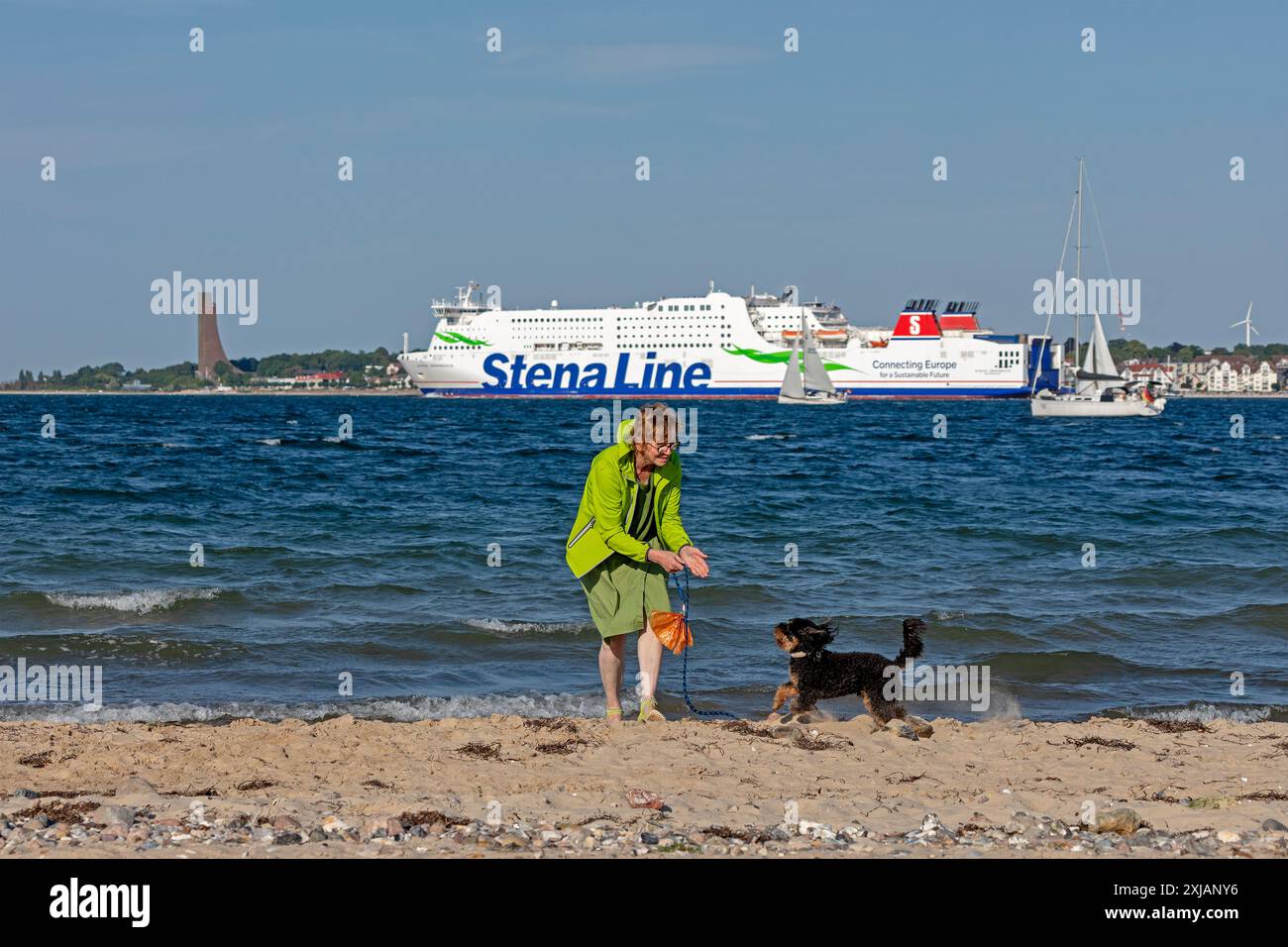 Ältere Frau spielt mit Hund, Navy Memorial, Laboe, Stena Line Fähre, Segelboot, Falckenstein Beach, Kieler Fjord, Kiel, Schleswig-Holstein, Deutschland Stockfoto