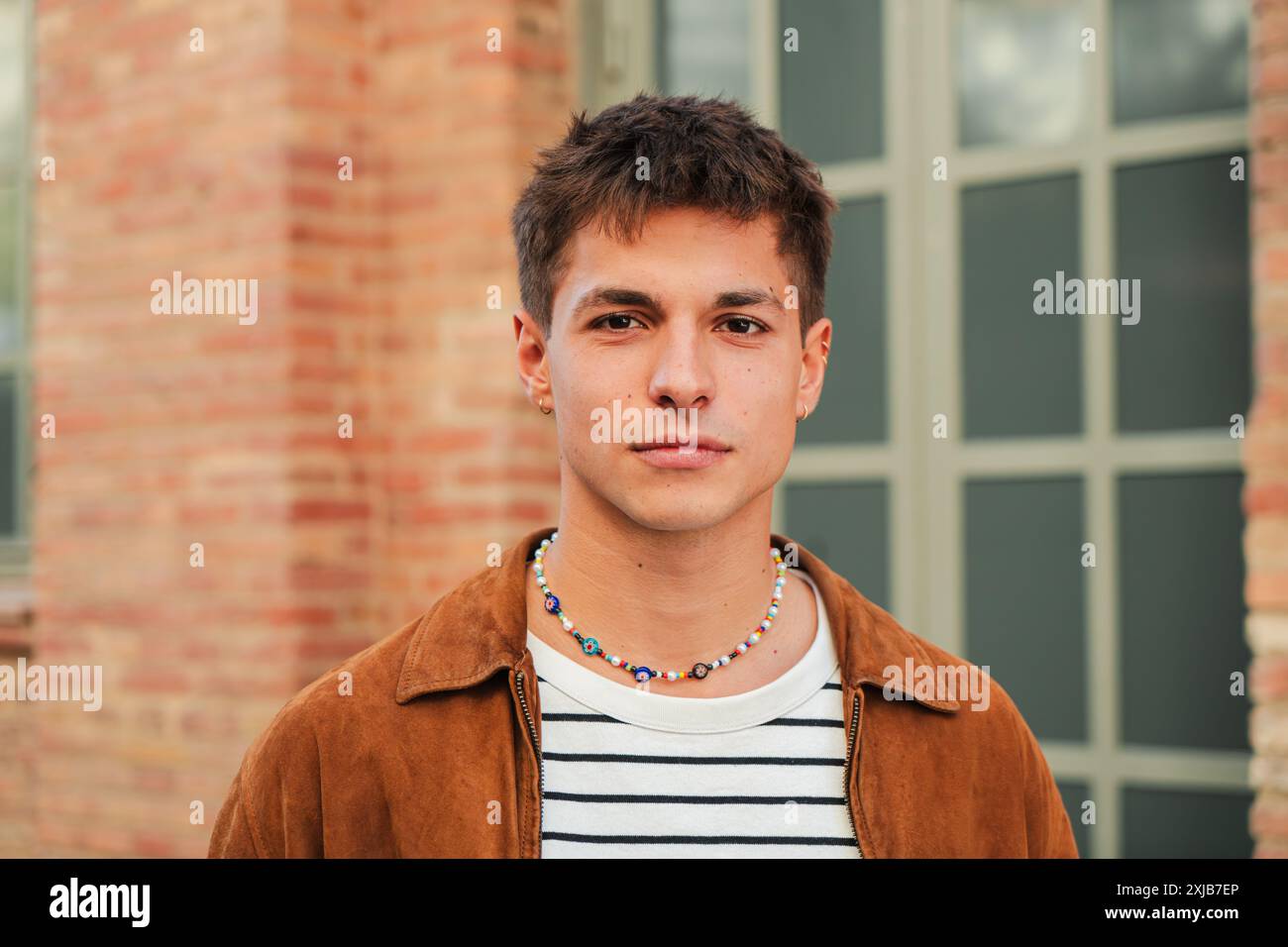 Junger Erwachsener an der Akademie. Individuelles Porträt eines ernsthaften Schuljungen, der in die Kamera blickt, die in der High School steht. Ein nachdenklicher männlicher Student im Teenageralter starrt nach vorne. Nachdenklicher Mann auf dem Universitätscampus. Hochwertige Fotos Stockfoto