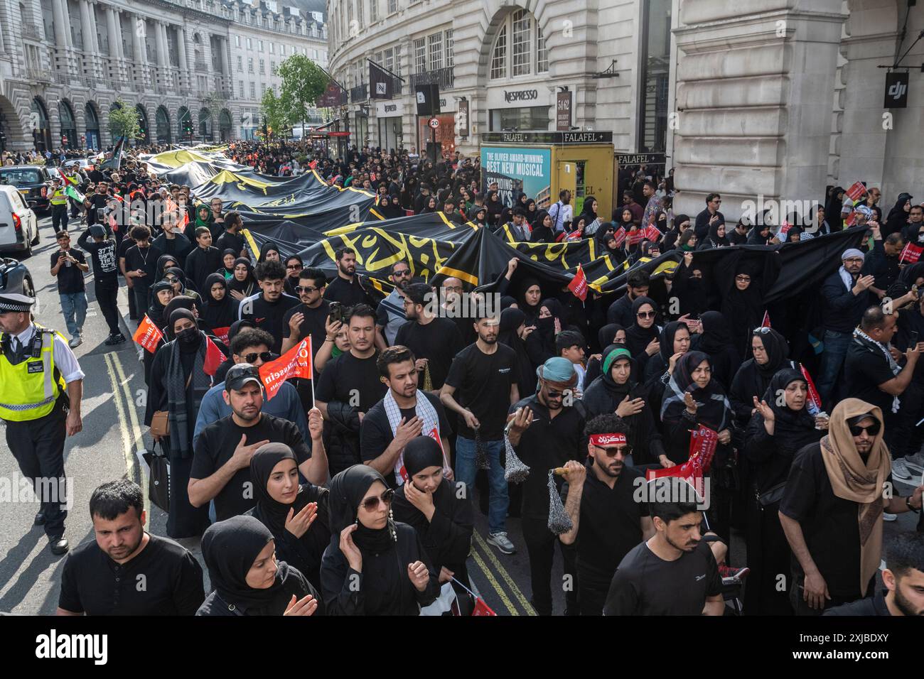 London, Großbritannien. 17. Juli 2024. Eine riesige Flagge wird auf der Regent Street getragen, während Zehntausende britische Muslime an dem Martyrium von Hussain, dem Enkel des Propheten Mohammed, an dem zehnten Tag auf Arabisch, erinnern. Dieses friedliche Ereignis wird weltweit jährlich gefeiert, bei dem Menschen in Erinnerung gehen. In der Hauptstadt führte der Weg von Marble Arch nach Whitehall. Quelle: Stephen Chung / Alamy Live News Stockfoto