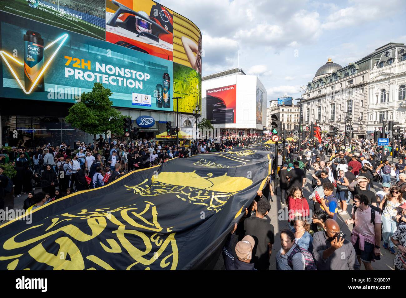 London, Großbritannien. 17. Juli 2024. Eine riesige Flagge wird durch den Piccadilly Circus getragen, während Zehntausende britische Muslime an dem Martyrium von Hussain, dem Enkel des Propheten Mohammed, an dem zehnten Tag auf Arabisch, erinnern. Dieses friedliche Ereignis wird weltweit jährlich gefeiert, bei dem Menschen in Erinnerung gehen. In der Hauptstadt führte der Weg von Marble Arch nach Whitehall. Quelle: Stephen Chung / Alamy Live News Stockfoto