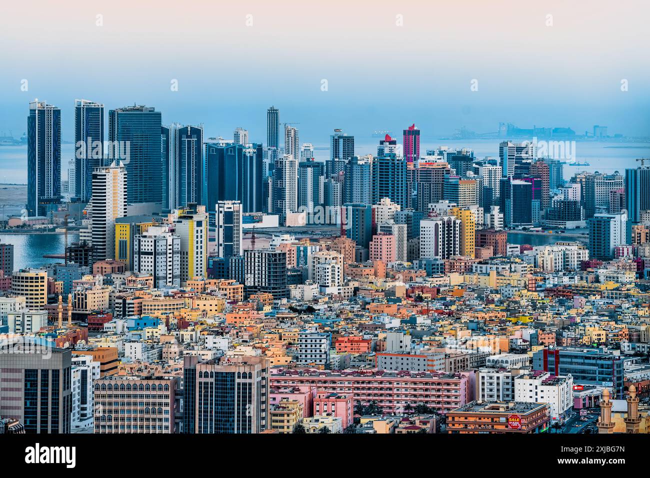 Manama, Bahrain bei Sonnenuntergang mit Megacity-Skyline, Wolkenkratzern, moderner Architektur, leuchtenden Lichtern der Stadt und urbanem Golf-Flair Stockfoto