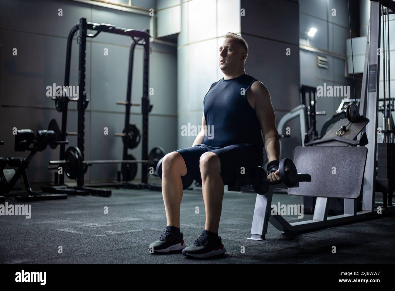 Mann, der Gewichte während eines Workouts in einem modernen Fitnessstudio hebt Stockfoto