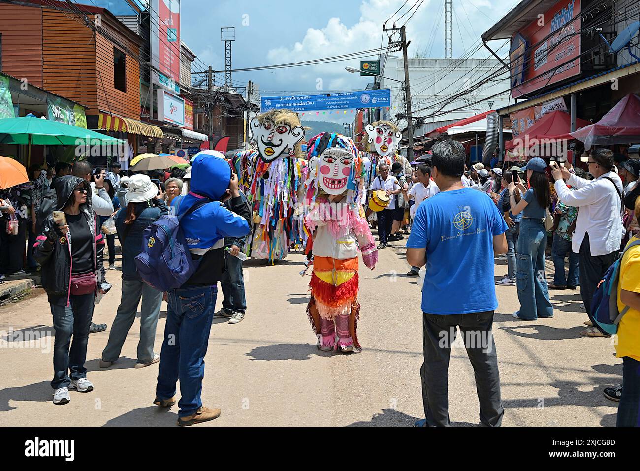 Menschenmassen begrüßen die Prozession von großen Kopfgeistern die Hauptstraße hinunter beim Phi Ta Khon Festival in Dan Sai, Loei, Thailand Stockfoto