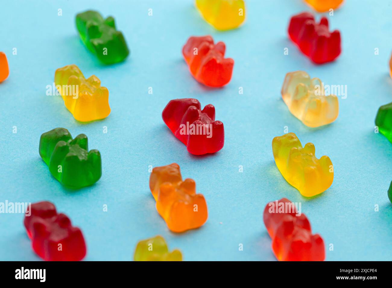 Regenbogenfarbene bärenförmige Gummibonbons isoliert auf blauem Hintergrund Stockfoto
