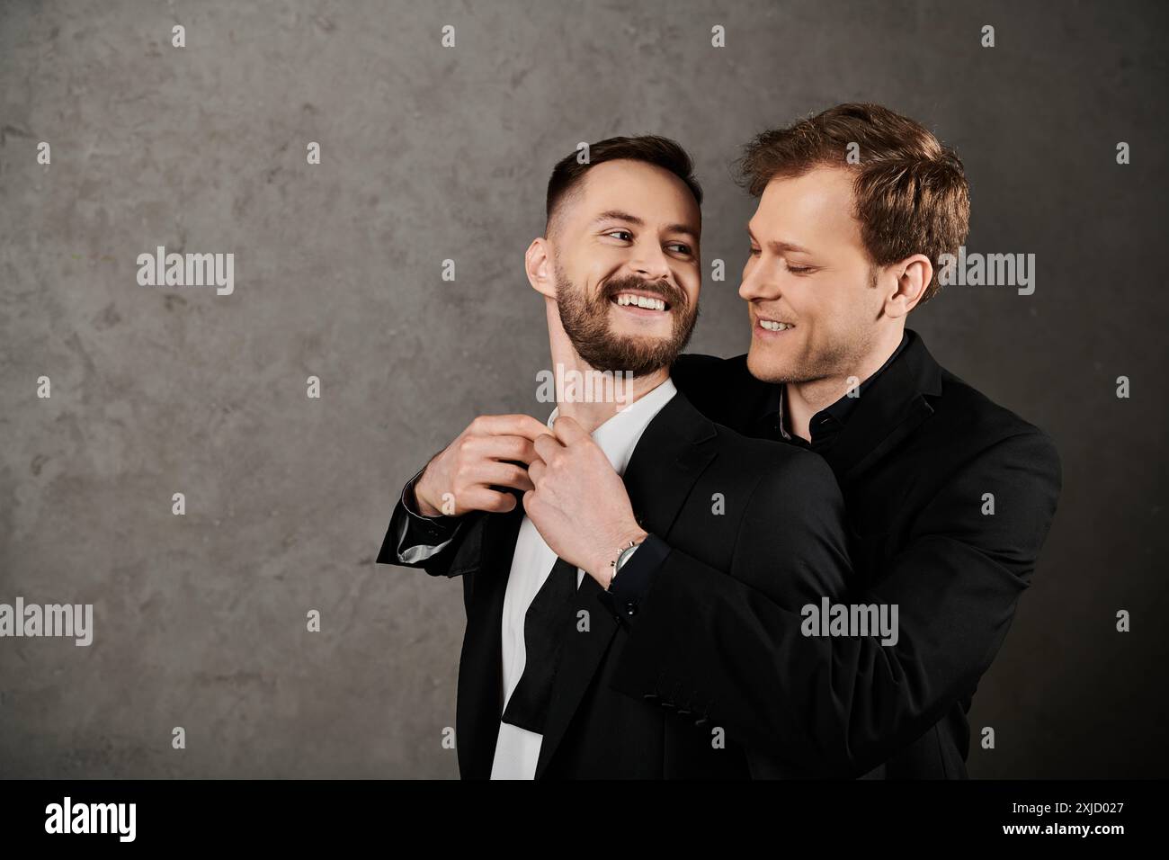 Zwei Männer in Anzügen umarmen und lachen zusammen, ihre Gesichter voller Freude. Stockfoto