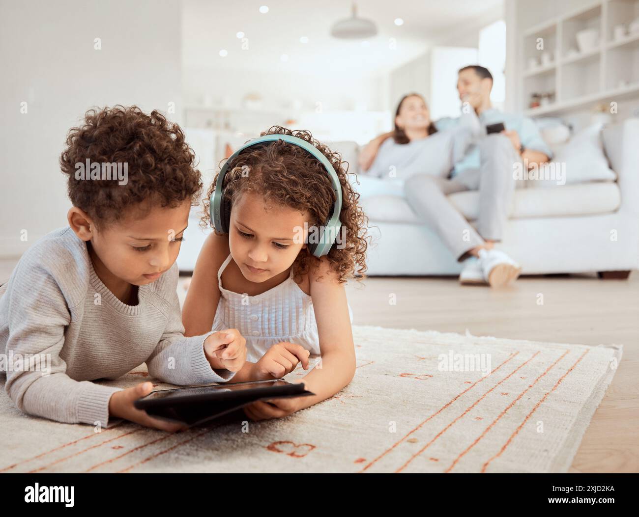 Geschwister, Tablet und Familienhaus mit Lernspiel und App für Lernentwicklung und Wachstum. Wohnzimmer, Eltern und entspannen mit Kindern, Technik Stockfoto