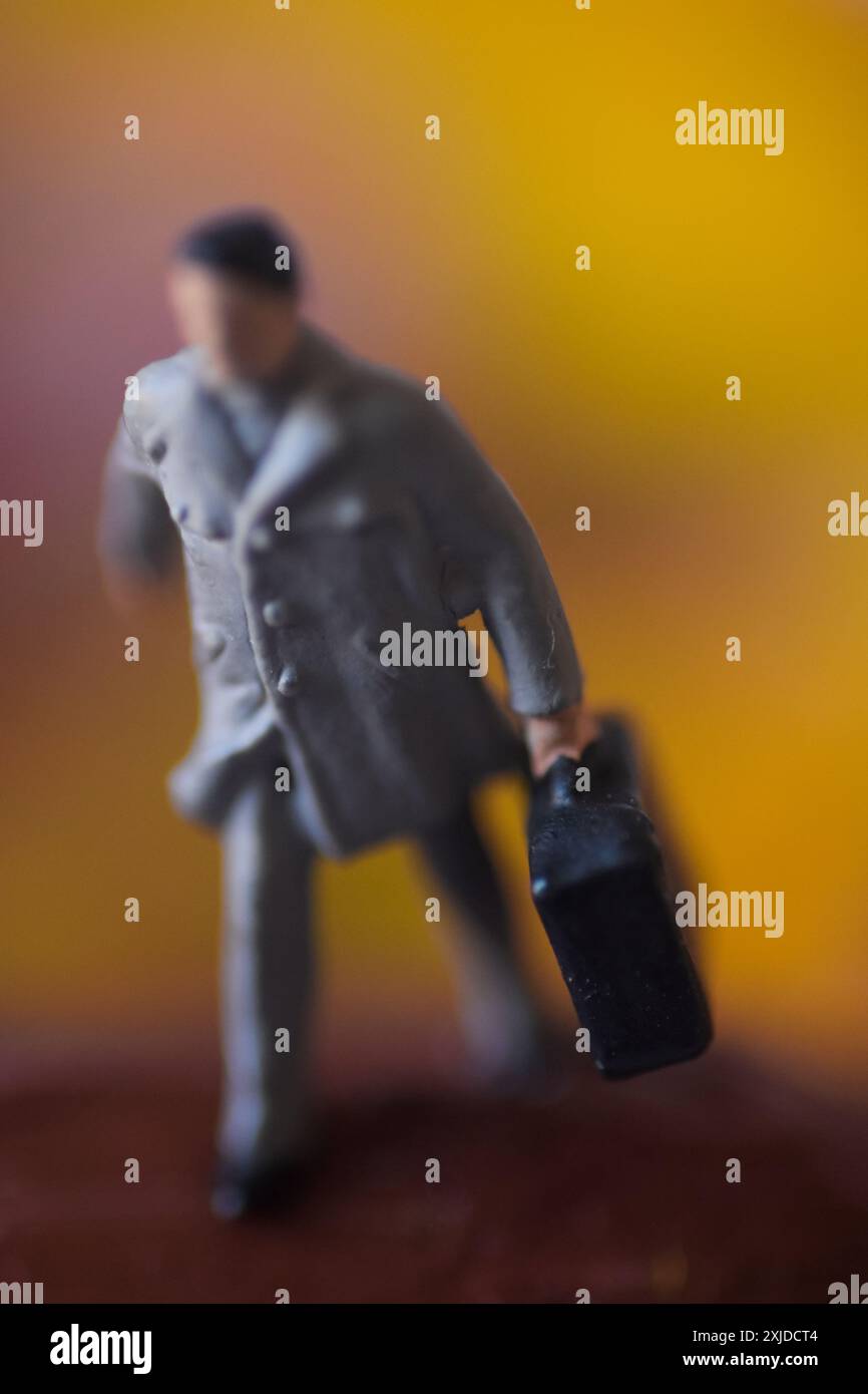 Miniaturfigur eines Mannes, der mit Koffer geht. Stockfoto