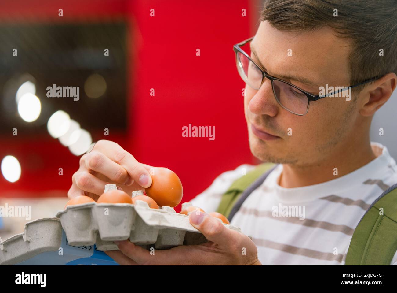 Mann kontrolliert Eier in einem Supermarkt und überprüft beim Einkaufen auf Qualität und Frische. Stockfoto