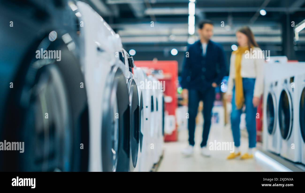 Multikulturelles Paar bewertet Waschmaschinenauswahl im Home Electronics Store. Mann und Frau auf der Suche nach einem zuverlässigen Waschgerät. Kunden erkunden moderne Wäschelösungen in einem Einzelhandel Stockfoto