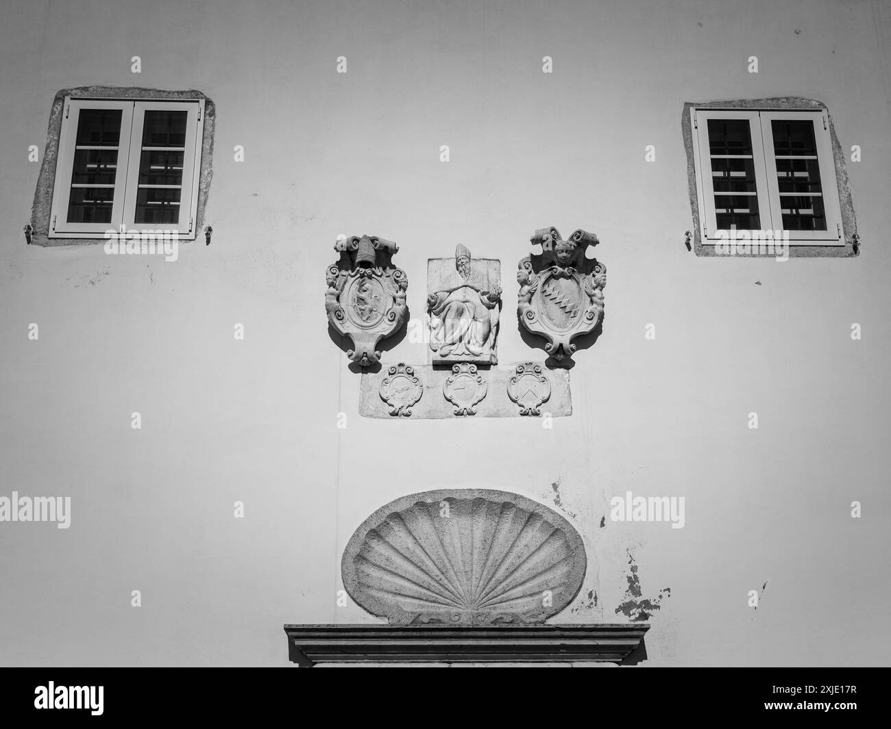 Eine Mauer aus einem Haus mit alten Statuen und Fenstern bei Tageslicht Stockfoto