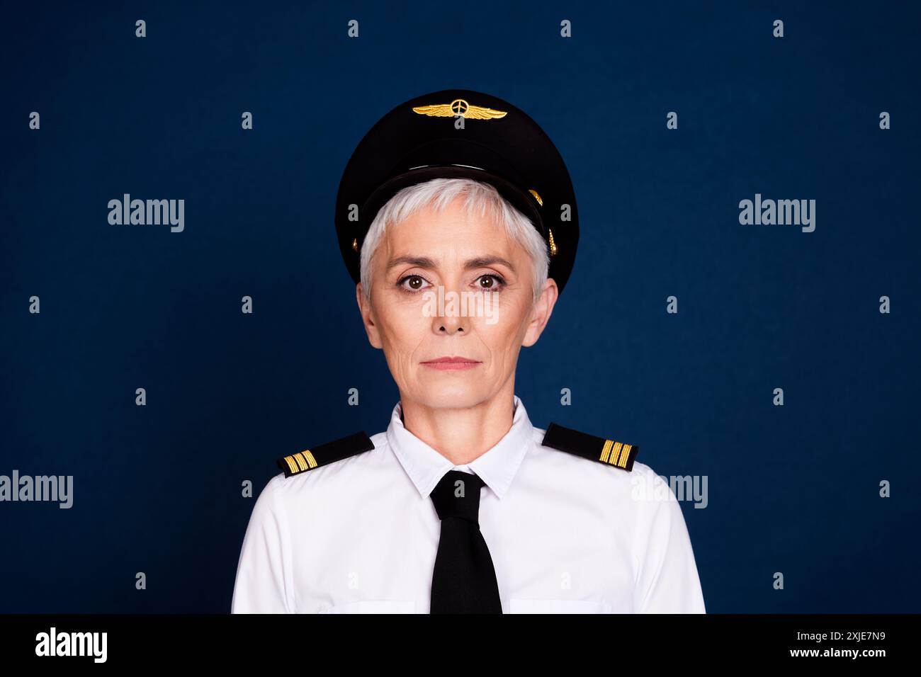 Foto-Porträt der hübschen pensionierten weiblichen professionellen Flugzeugpiloten tragen Pilotenuniform isoliert auf dunkelblauem Hintergrund Stockfoto