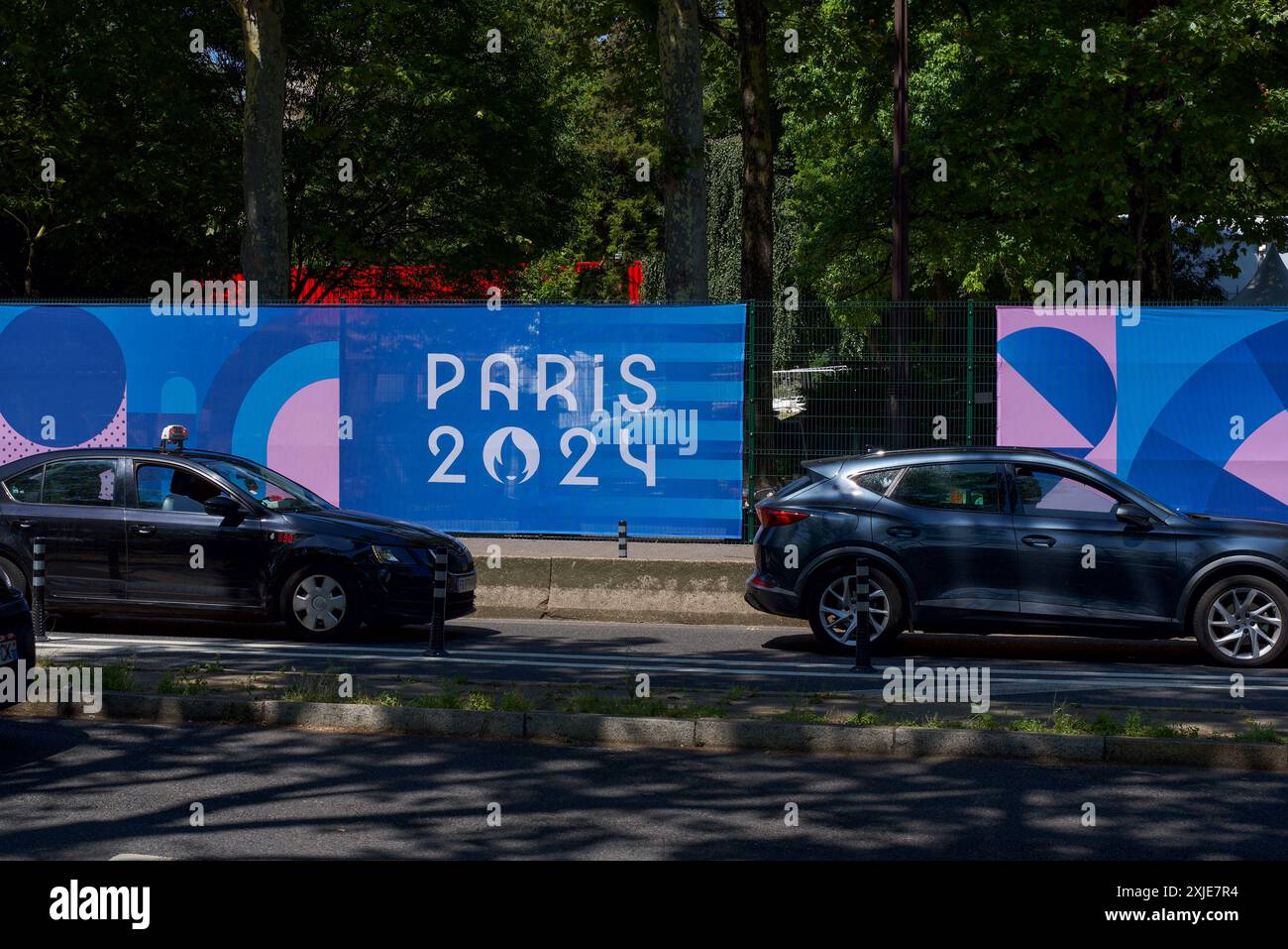 Ein Banner für die Olympischen Spiele 2024 in Paris hängt am Straßenrand im Zentrum von Paris. Vorbeifahrende Autos. Stockfoto