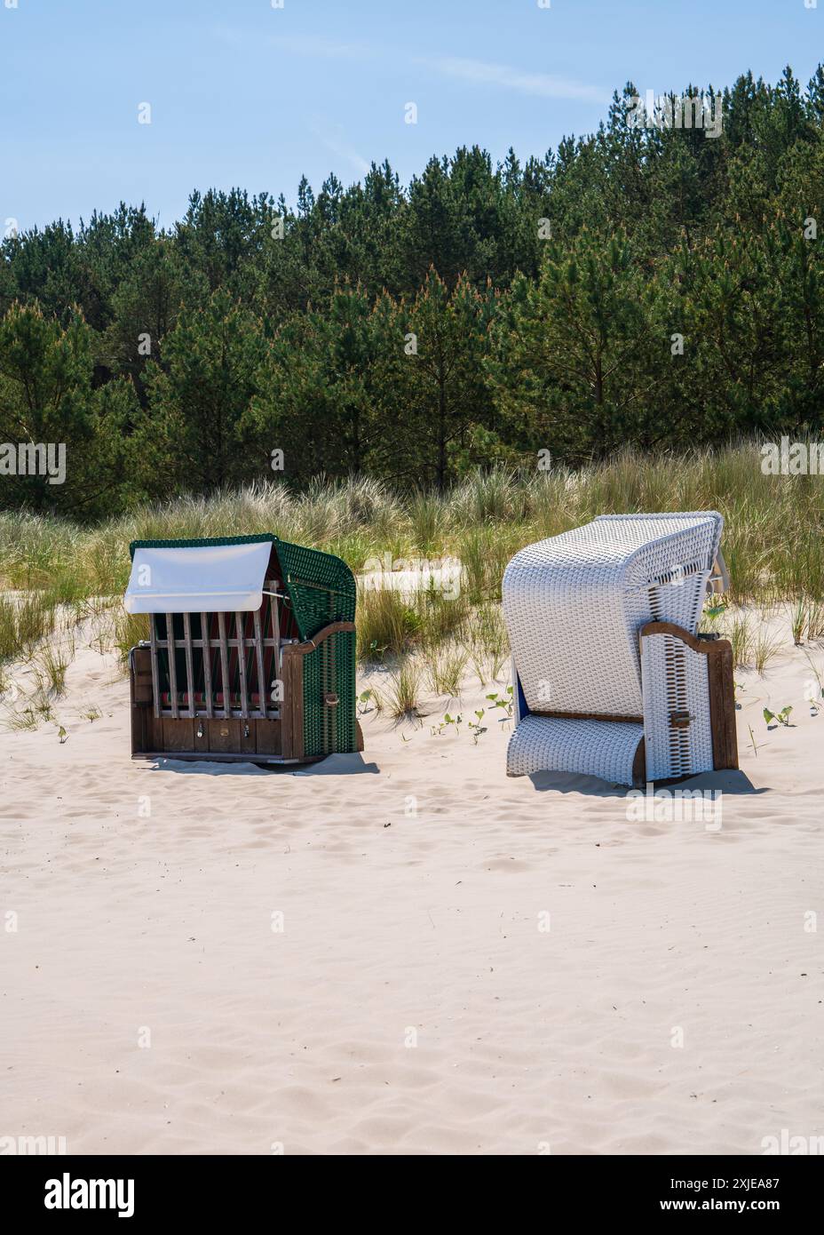 Am Sandstrand gibt es zwei Strandkorbs, die in verschiedene Richtungen zeigen. Schutz vor Wind und Sonne. Ostsee, Deutschland. Stockfoto
