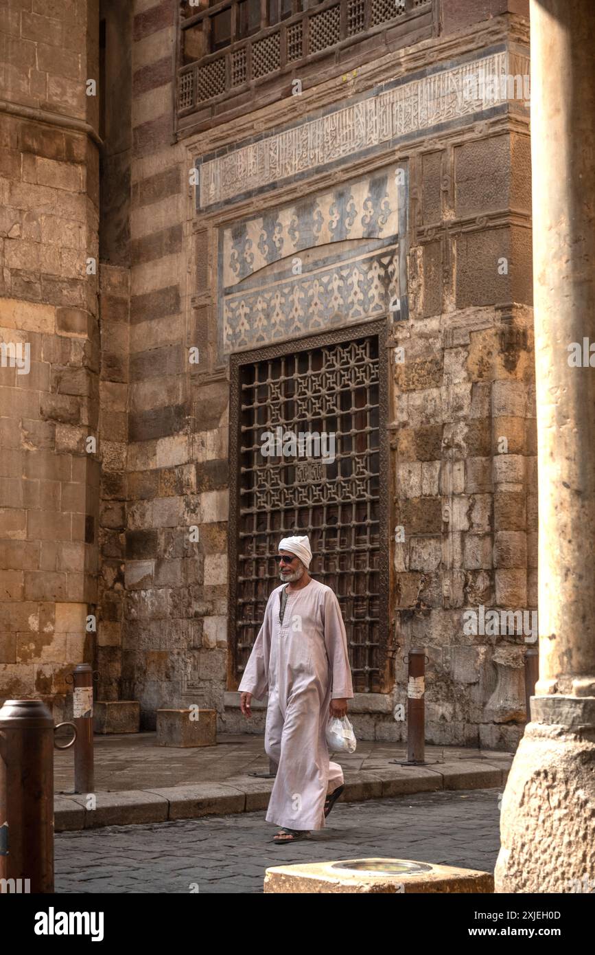 Kairo, Ägypten. 7. Juli 2024 ein ägyptischer Mann in traditioneller Kleidung spaziert durch die Kopfsteinpflasterstraßen des islamischen Kairos, einem historischen Viertel und der UNO Stockfoto