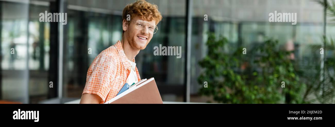 Ein Mann geht gemütlich die Straße hinunter und hält ein Buch. Stockfoto