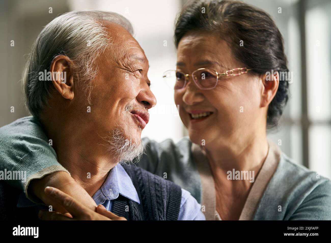 Porträt eines glücklichen liebenden asiatischen Seniorenpaares, das zu Hause auf der Couch sitzt Stockfoto