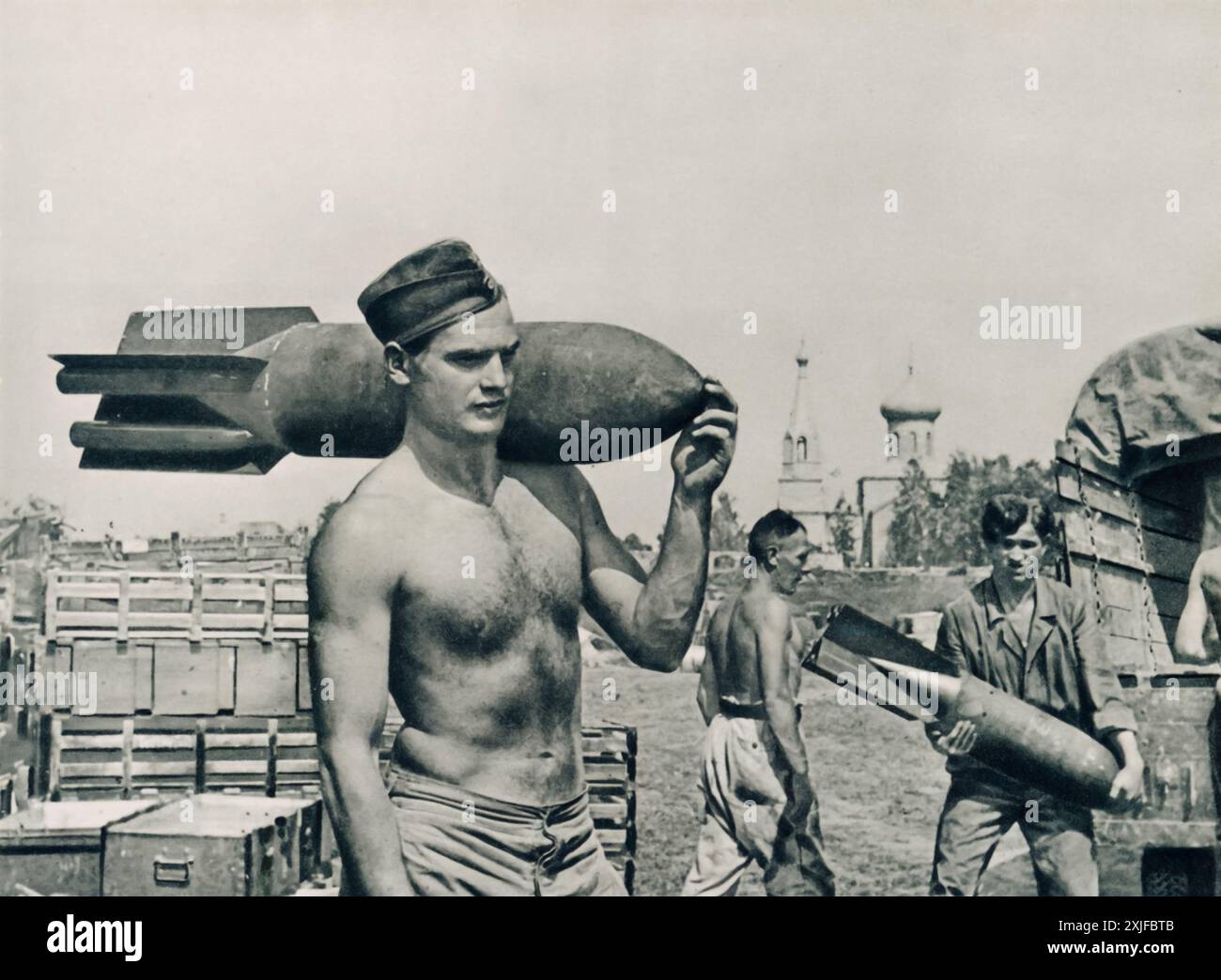 Ein Foto zeigt einen deutschen Soldaten, der eine Bombe auf der Schulter trägt und sich darauf vorbereitet, Flugzeuge an ihren Parkplätzen aufzufüllen. Dieses Bild wurde 1941 während der Operation Barbarossa aufgenommen und zeigt die anhaltenden Bemühungen, Luftwaffenflugzeuge zu bewaffnen, während die deutschen Truppen während des Zweiten Weltkriegs gegen sowjetische Truppen an der Ostfront vorrückten. Stockfoto