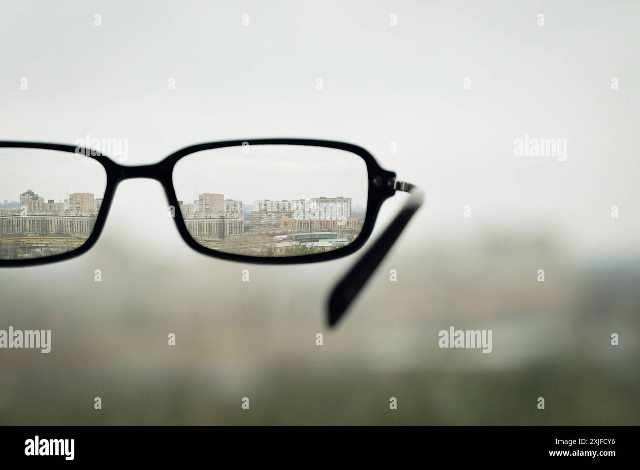 Schlechte Sehkraft. Selektives fokussiertes Bild mit unfokussierter Brille und scharfer Stadtlandschaft im Hintergrund. Stockfoto