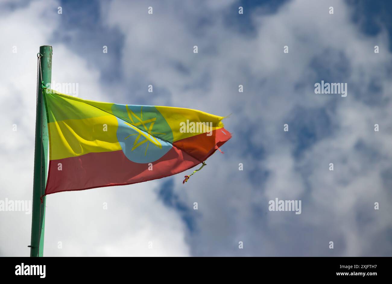 Die äthiopische Flagge mit ihren grünen, gelben und roten Streifen und dem zentralen Emblem winkt stolz im Wind vor einem bewölkten Himmel Stockfoto