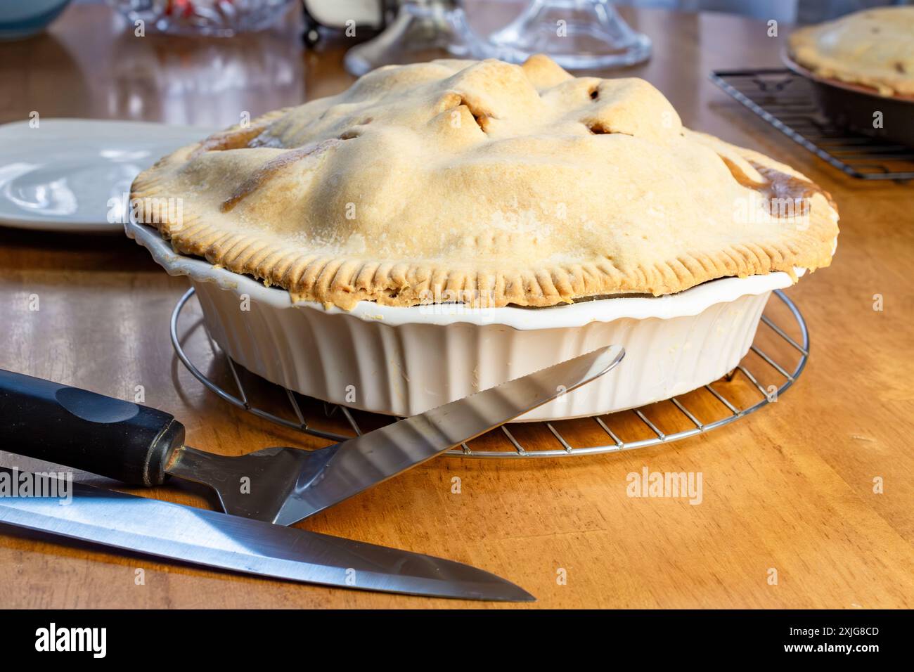 Apfelkuchen machen: Den Kuchen schneiden. Der Messer-und-Kuchen-Server sitzt neben dem gekühlten Apfelkuchen. Stockfoto