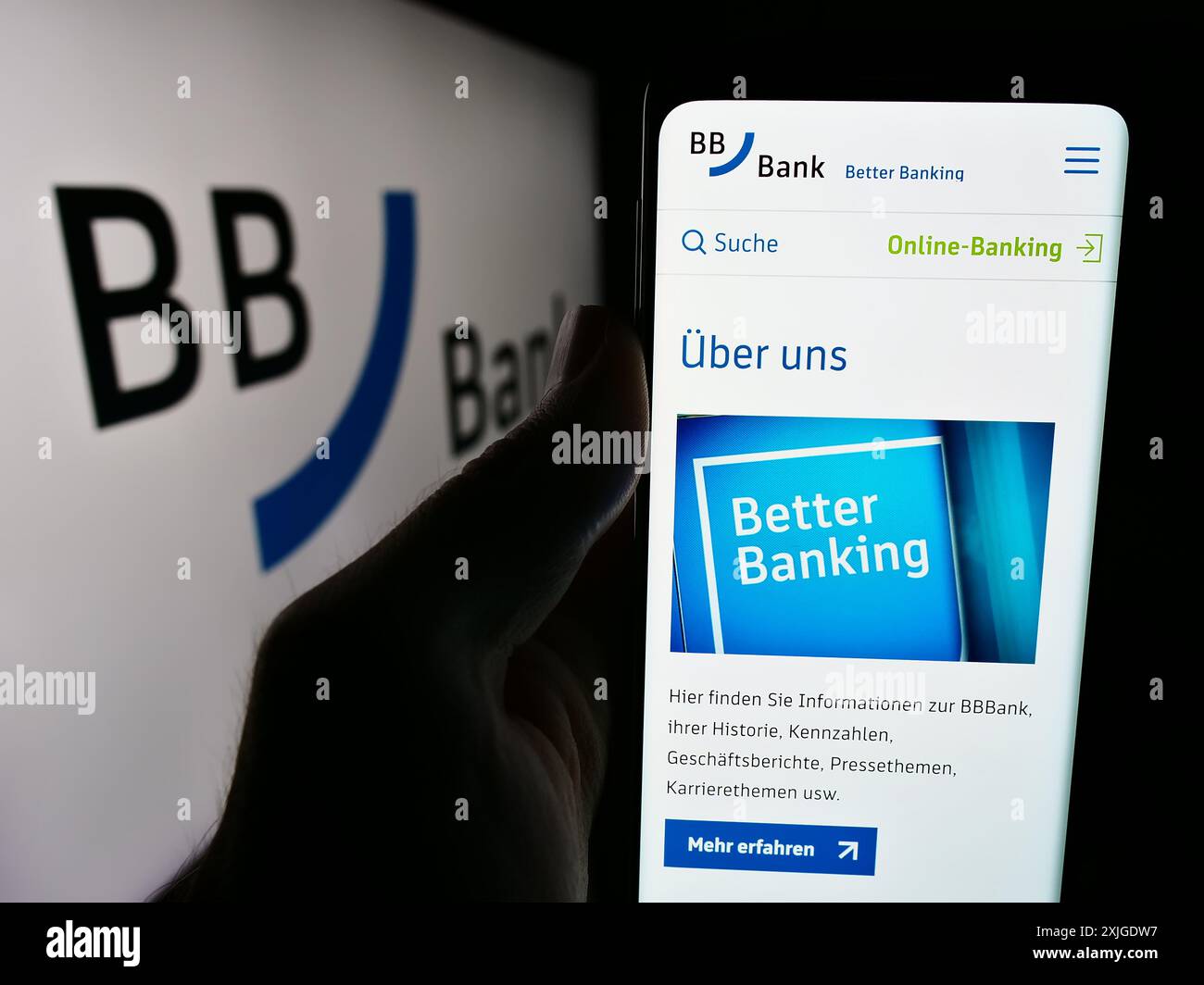 Person, die ein Mobiltelefon mit Webseite des deutschen Finanzdienstleisters BBBank hält, z. B. vor dem Firmenlogo. Konzentrieren Sie sich auf die Mitte des Telefondisplays. Stockfoto