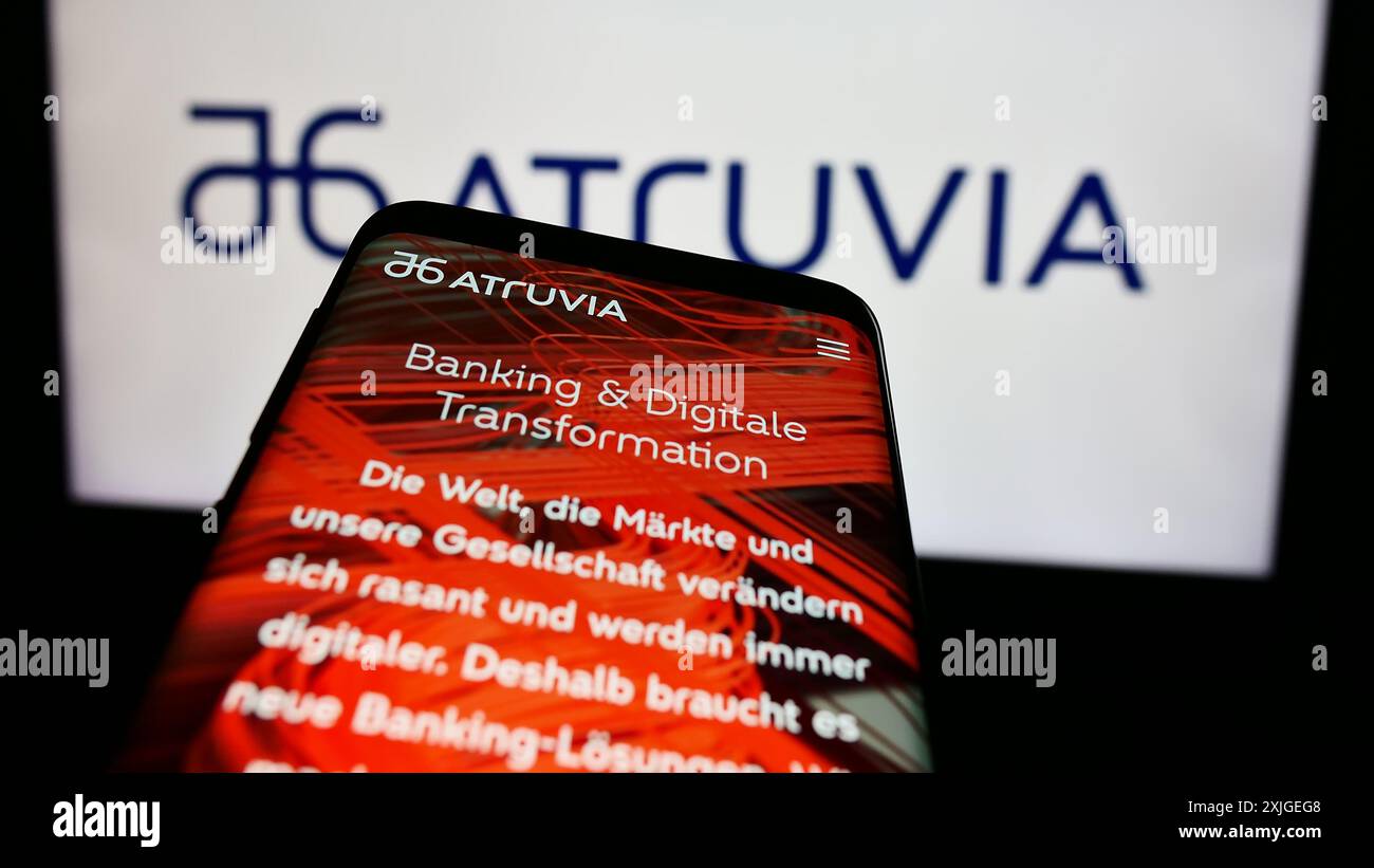 Mobiltelefon mit Website des deutschen IT-Unternehmens Atruvia AG vor Firmenlogo. Fokussieren Sie sich oben links auf der Telefonanzeige. Stockfoto