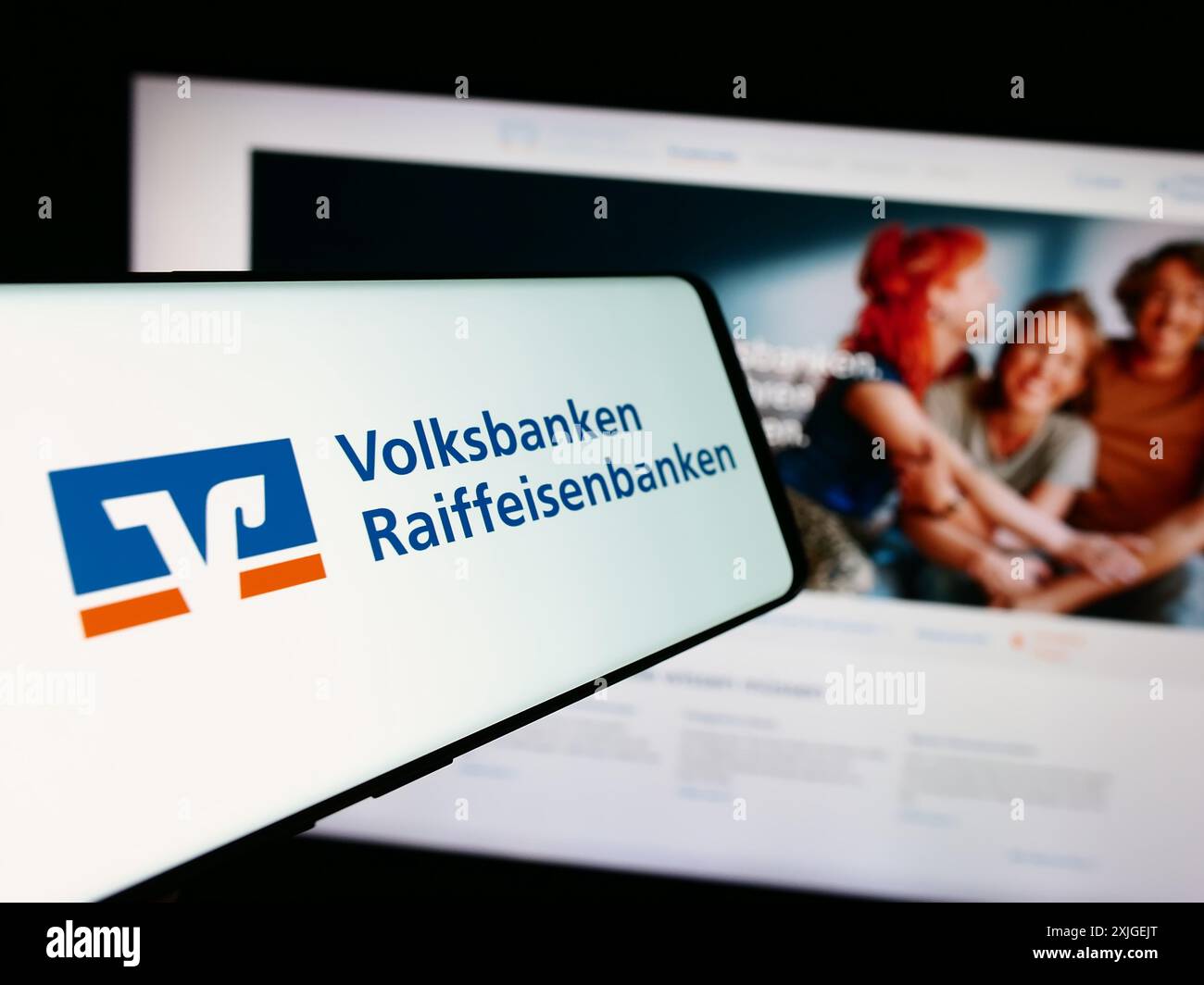 Mobiltelefon mit Logo des deutschen Bankennetzes Volksbanken Raiffeisenbanken vor der Website. Fokussieren Sie sich auf die linke Mitte des Telefondisplays. Stockfoto