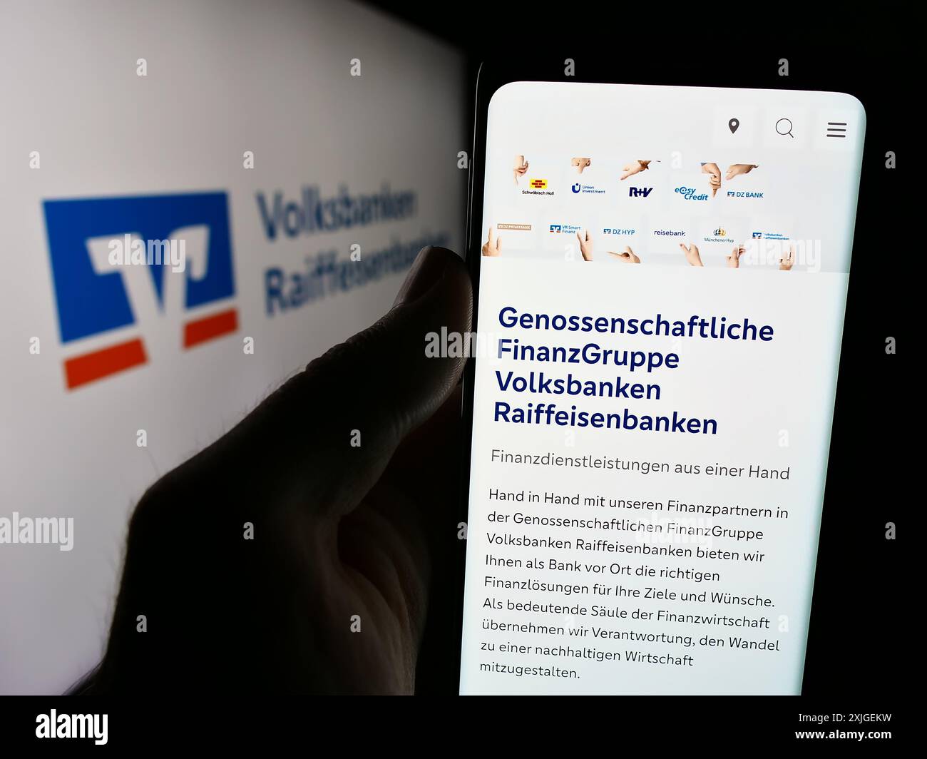 Handybesitzer mit Website des deutschen Banknetzes Volksbanken Raiffeisenbanken vor dem Logo. Konzentrieren Sie sich auf die Mitte des Telefondisplays. Stockfoto