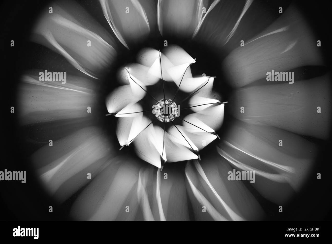 Abstrakter Hintergrund mit einer Wolframlampenspirale, die im Dunkeln leuchtet, Schwarzweiß-Makrofoto mit selektivem Weichfokus Stockfoto