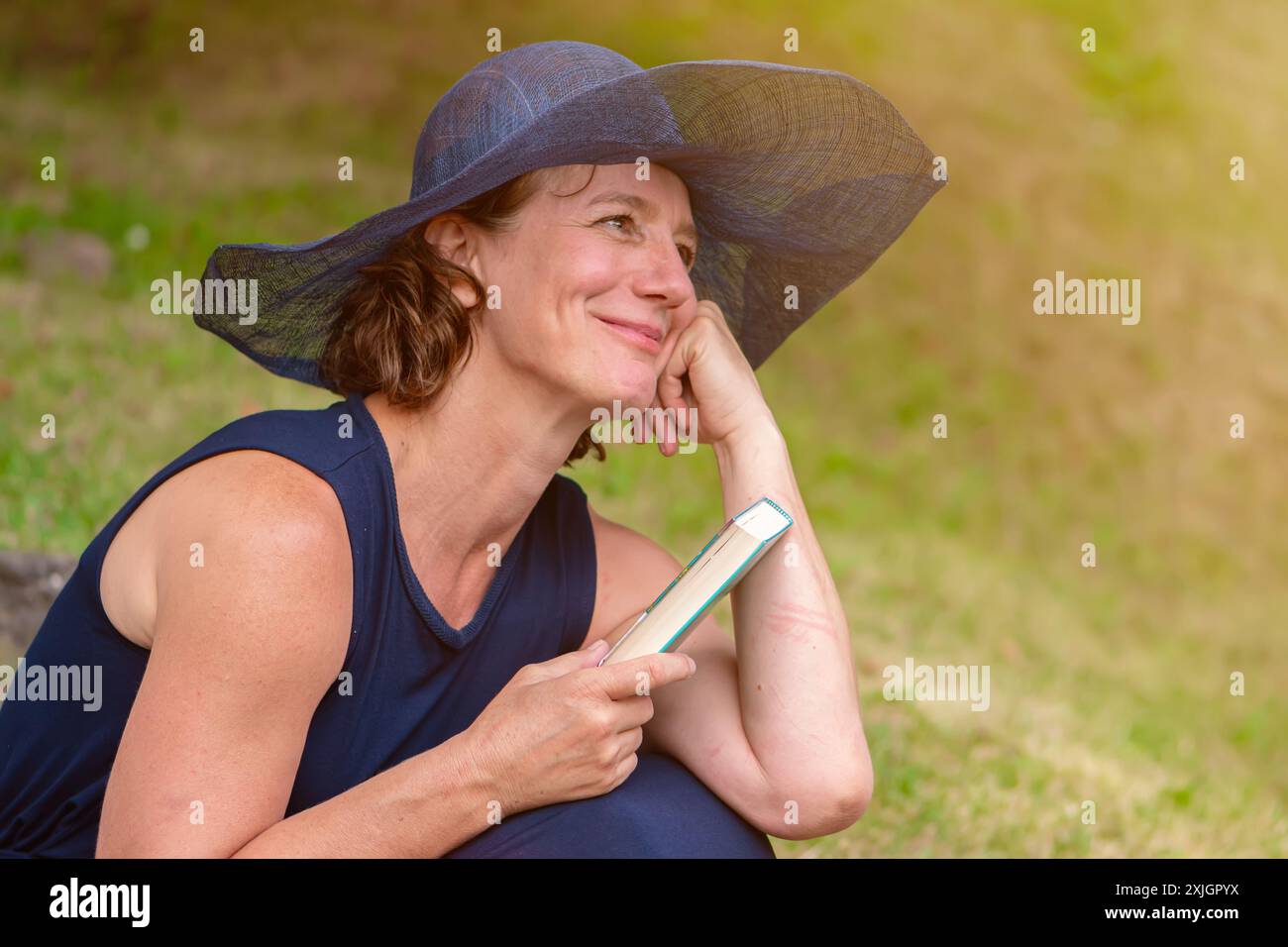 Porträt einer romantischen älteren Frau im Alter von 50-55 Jahren mit blauem Damenhut und einem Buch. Stockfoto