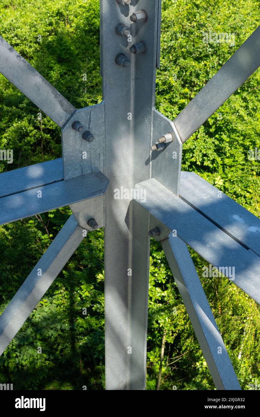 Schraubverbindungen von Stahlelementen des Aussichtsturms. Konstruktionsdetails aus verzinktem Stahl vor grünem Baumgrund Stockfoto