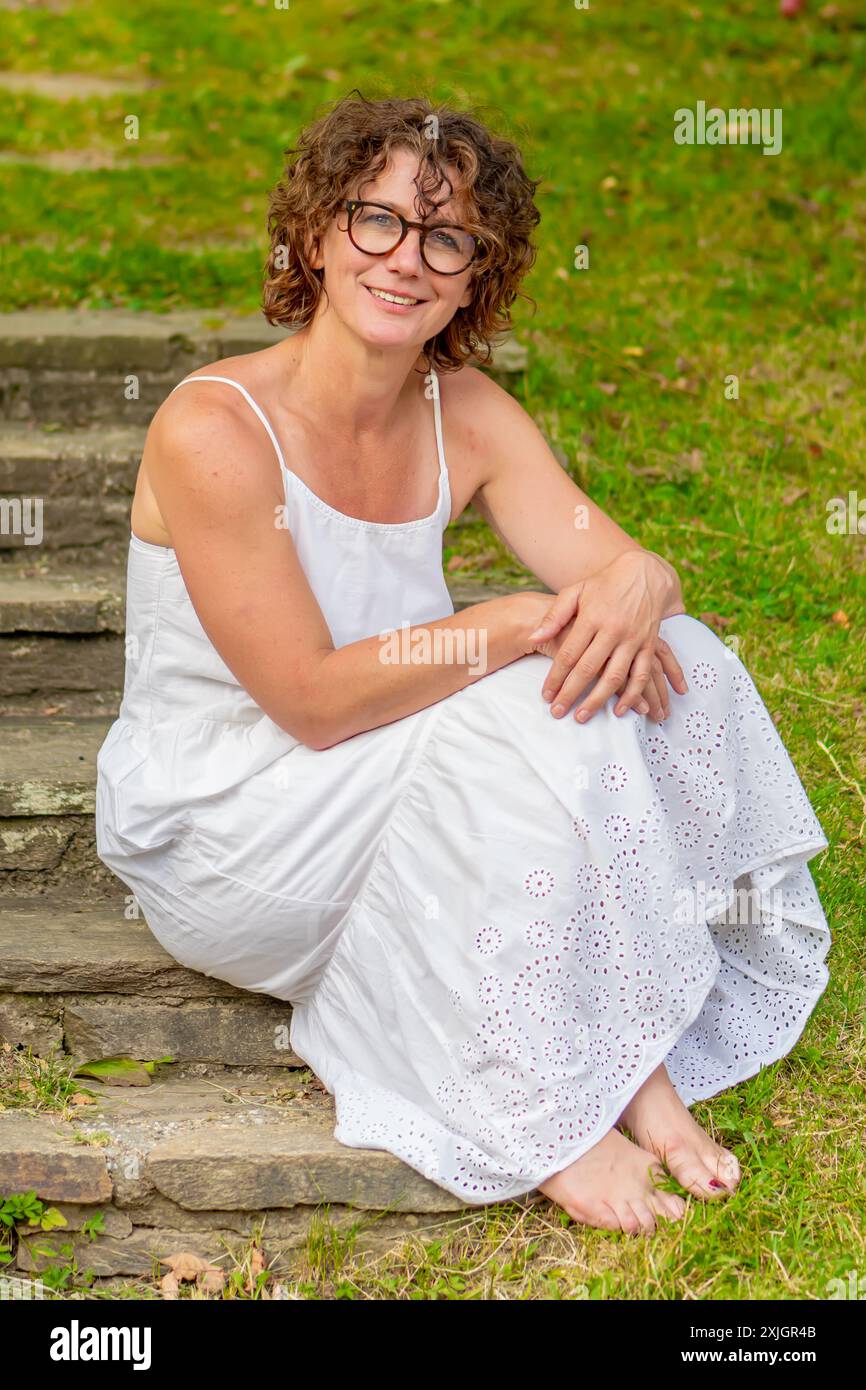 Frau in weißem Kleid, die auf Steinstufen sitzt Stockfoto