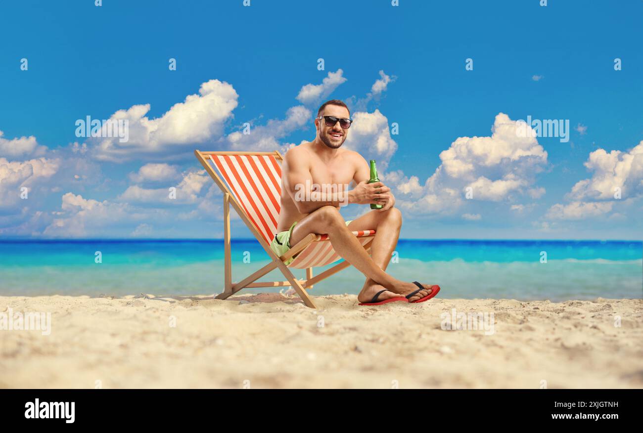 Ein Mann genießt ein Bier an einem Sandstrand am Meer Stockfoto