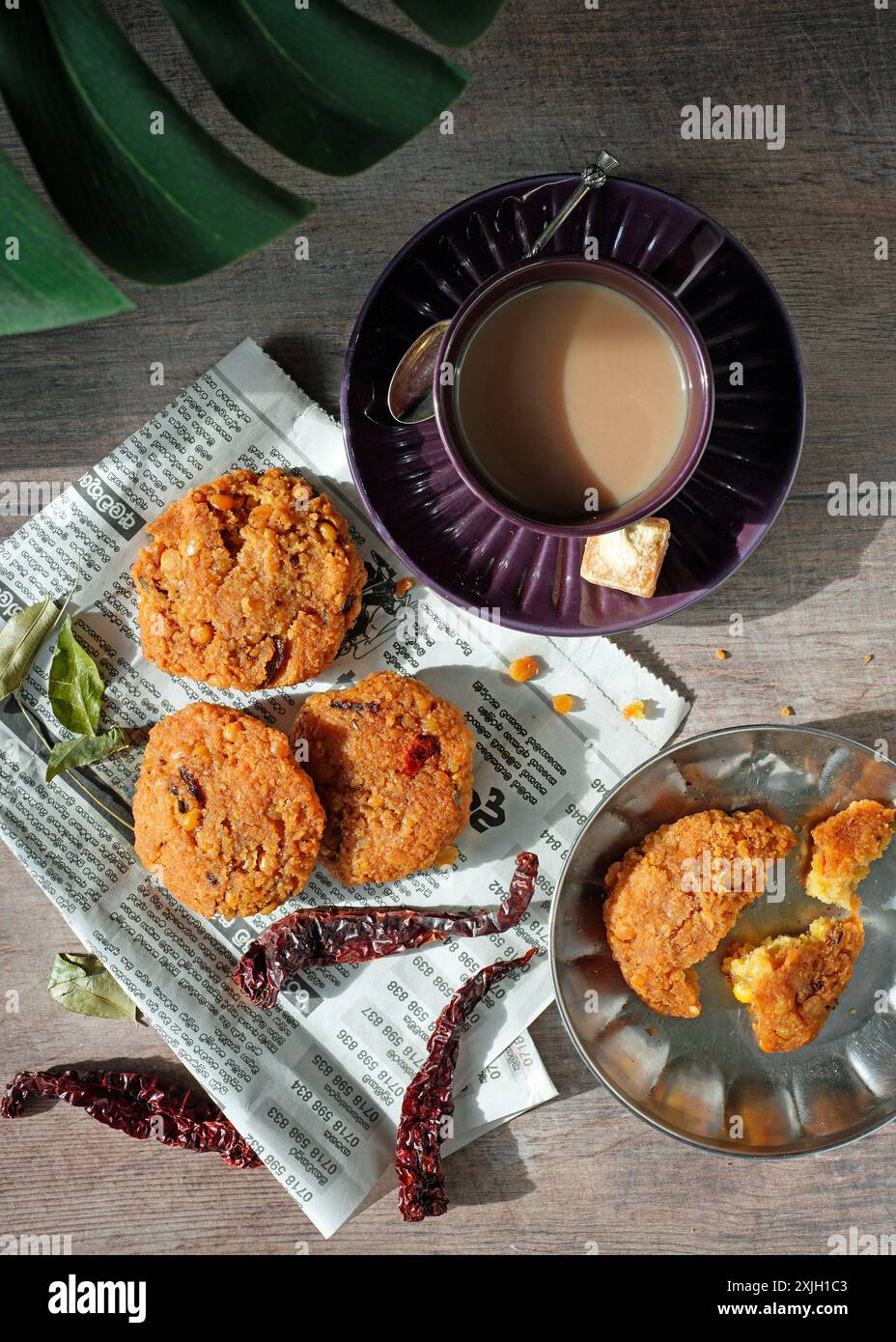 Top-Down-Flachbild des Sri-lankischen Vadai - ein herzhafter Snack aus chana Dhal (geteilte Kichererbsen), begleitet von einer Tasse heißen, süßen Milchtee. Stockfoto