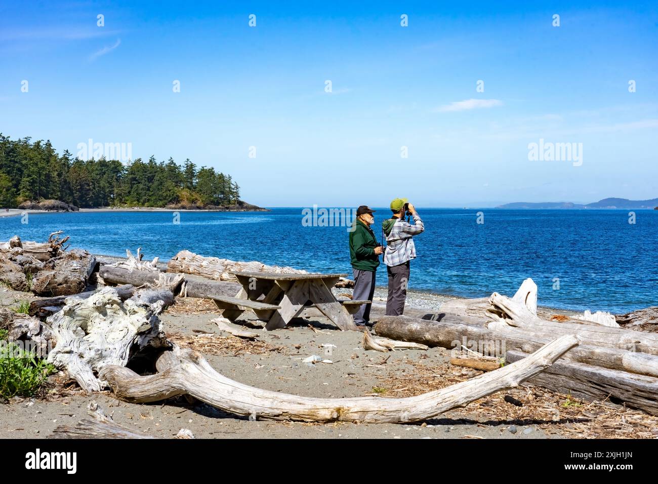 Täuschung Pass State Park, Washington, USA. Zwei Männer in North Beach beobachten Vögel am Meer Stockfoto