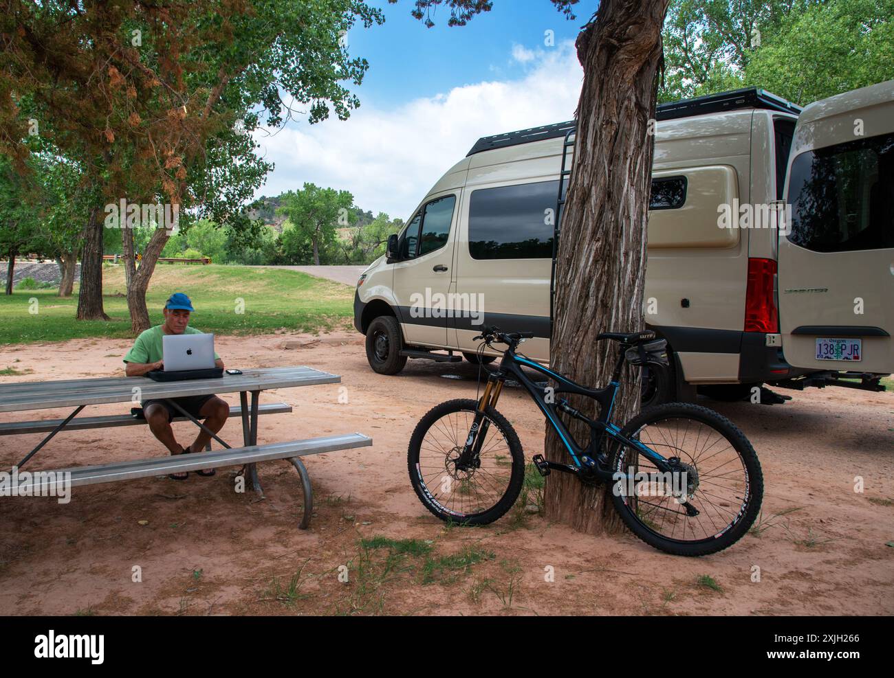 Ein Mann, der am Mac-Computer arbeitet, an einem Picknicktisch im Palo Duro Canyon State Park, Texas Stockfoto
