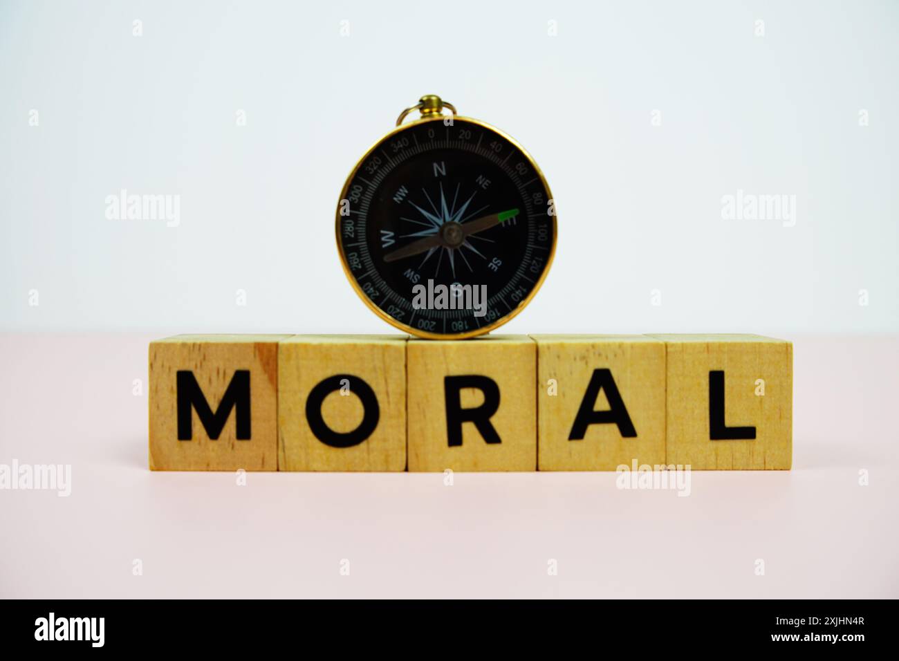 Kompass mit Holzblöcken Buchstaben MORAL auf rosa Hintergrund Stockfoto